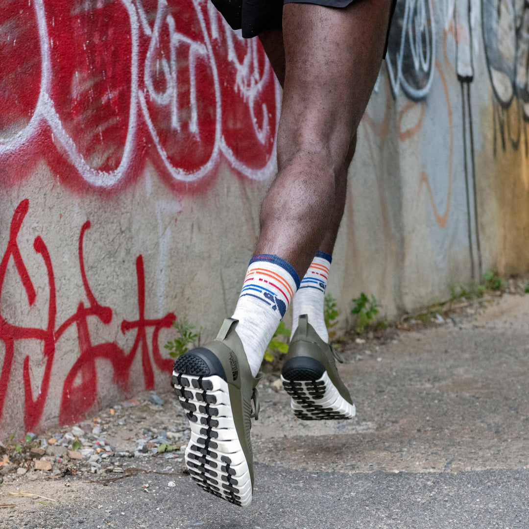 Close up shot of a model running in the street wearing the men's pacer micro crew running sock with olive green sneakers