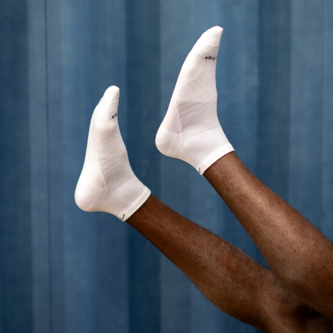 Close up shot of model's feet up in the sair wearing the men's quarter running sock in white
