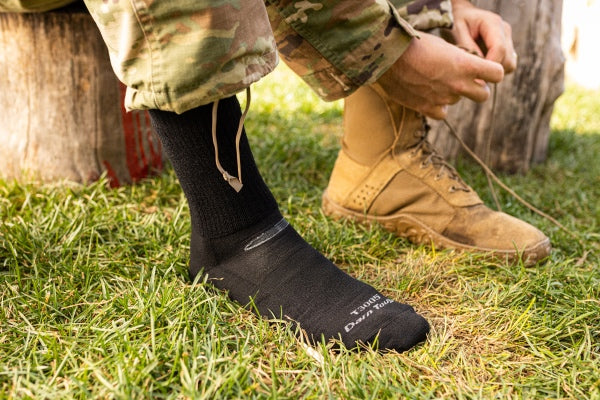 Soldier tying boot laces while wearing black lightweight tactical socks