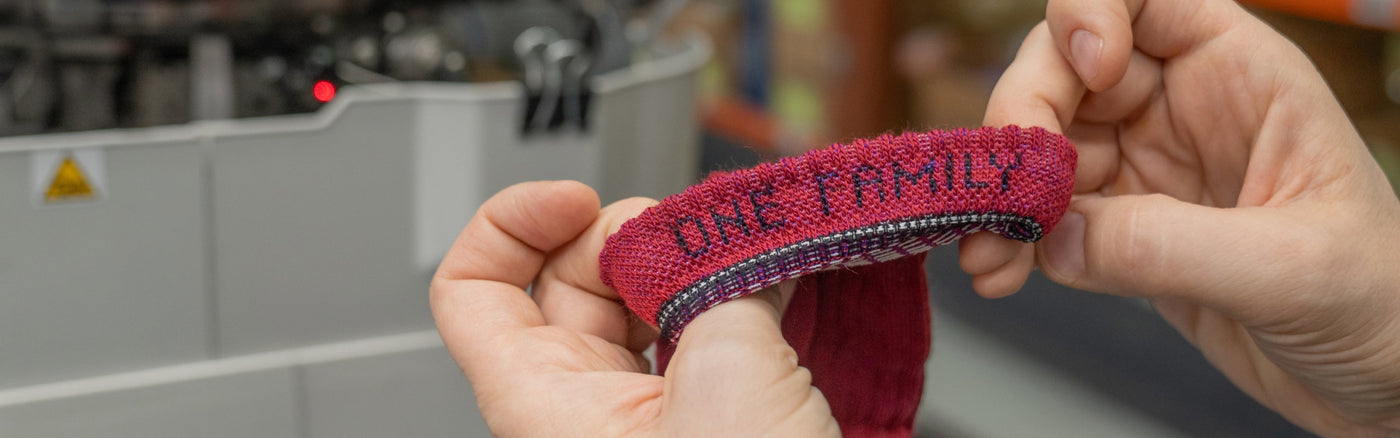 Hands showing inside of sock cuff, which says "One Family"