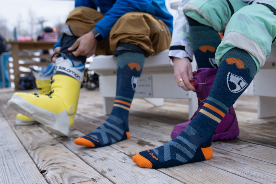 Two skiers wearing the High Fives sock in blue