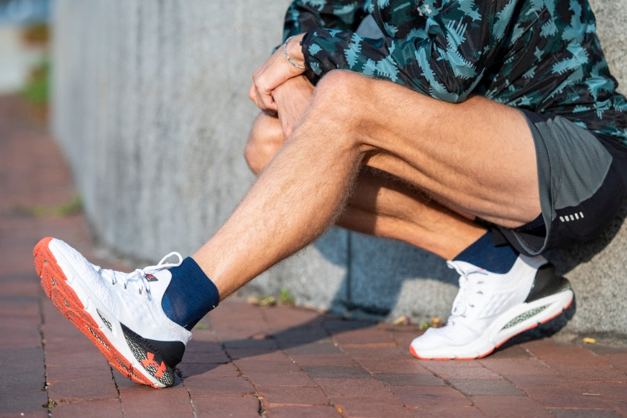 A runner stretching their legs while wearing the men's no cushion run quarters in dark blue