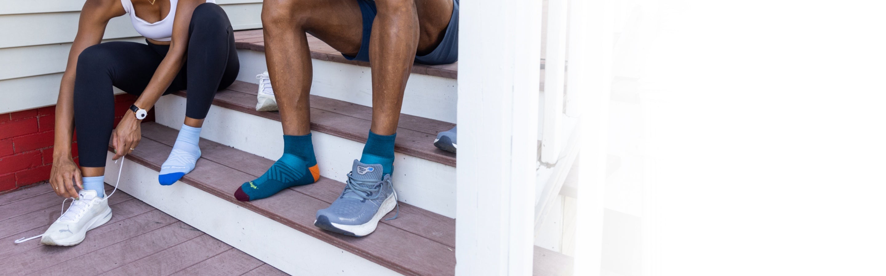 Two runners seated on steps pulling on sneakers over Run Quarter Socks from Darn Tough