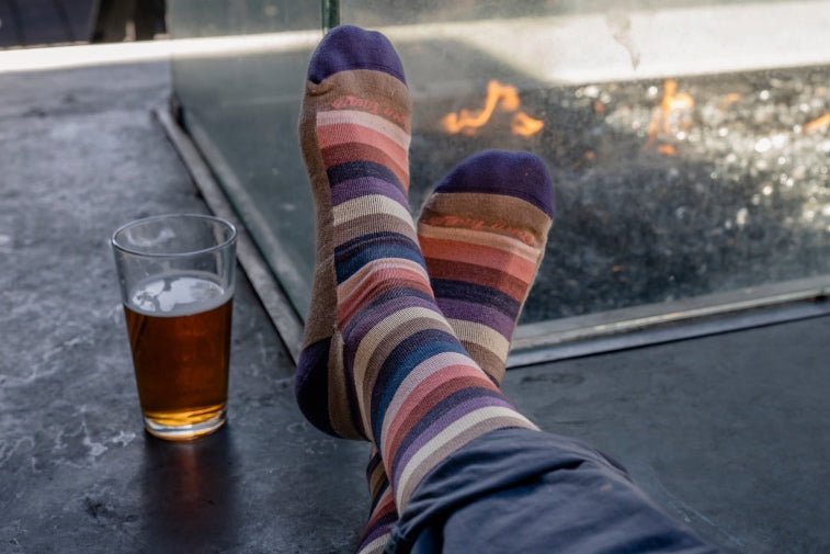 Shop Men's Lifestyle socks - crossed feet in striped socks next to a drink