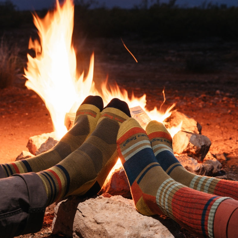 Two sets of feet up in front of a fire wearing Darn Tough socks, the perfect Valentine's Day evening