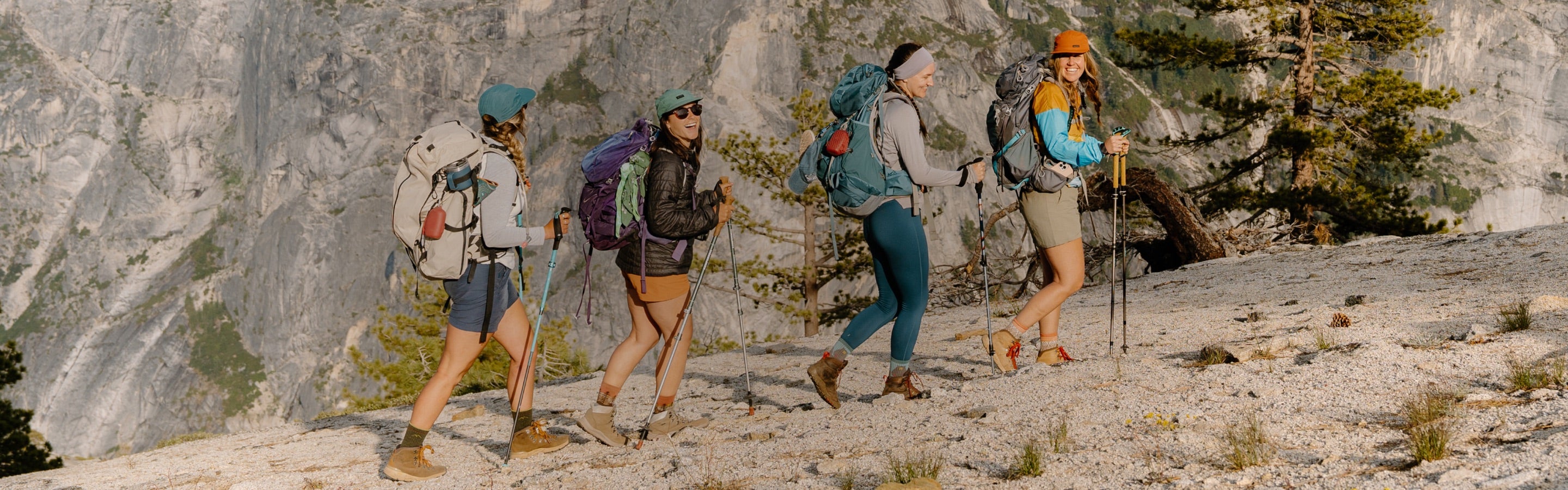 A group of hikers walking up a ridgeline together, laughing and smiling
