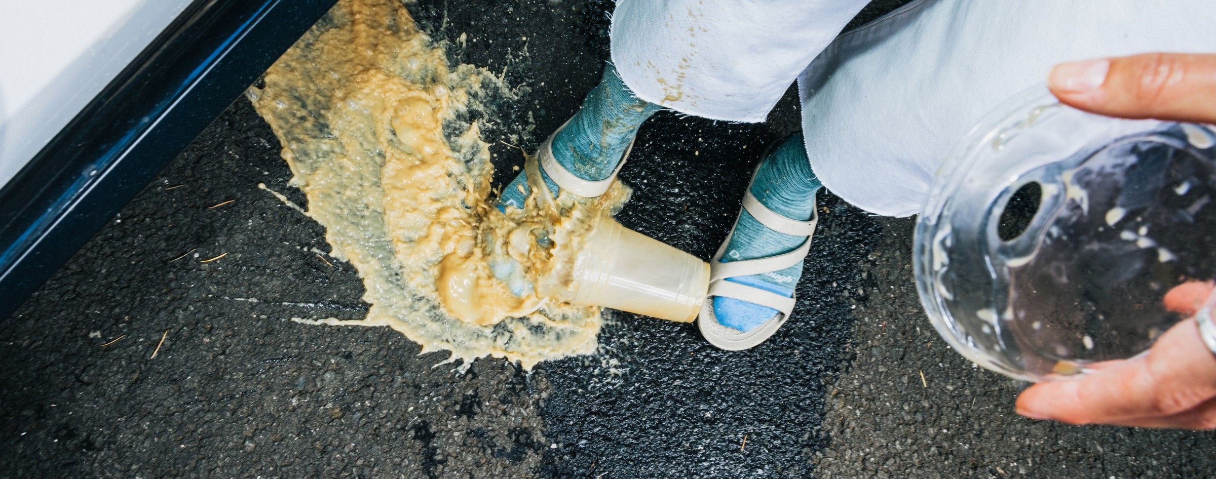 View from above of someone dropping their coffee all over their feet and socks