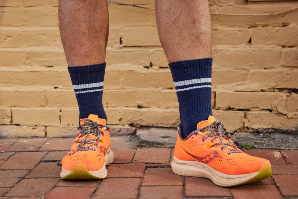 A pair of feet wearing lightweight merino wool run socks in a crew height