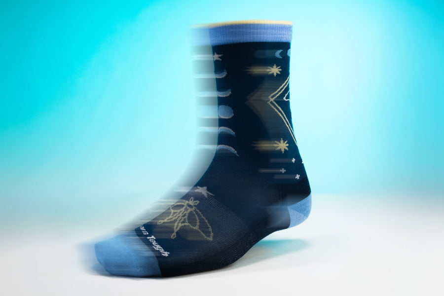 The Luna sock - a dark blue sock with a lunar moth design and phases of the moon in gold and lighter blue