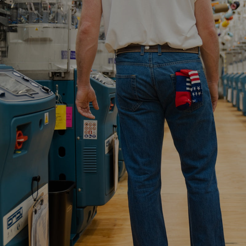 A close-up of someone standing in the Mill showing their back pocket which has a red white and blue sock in it