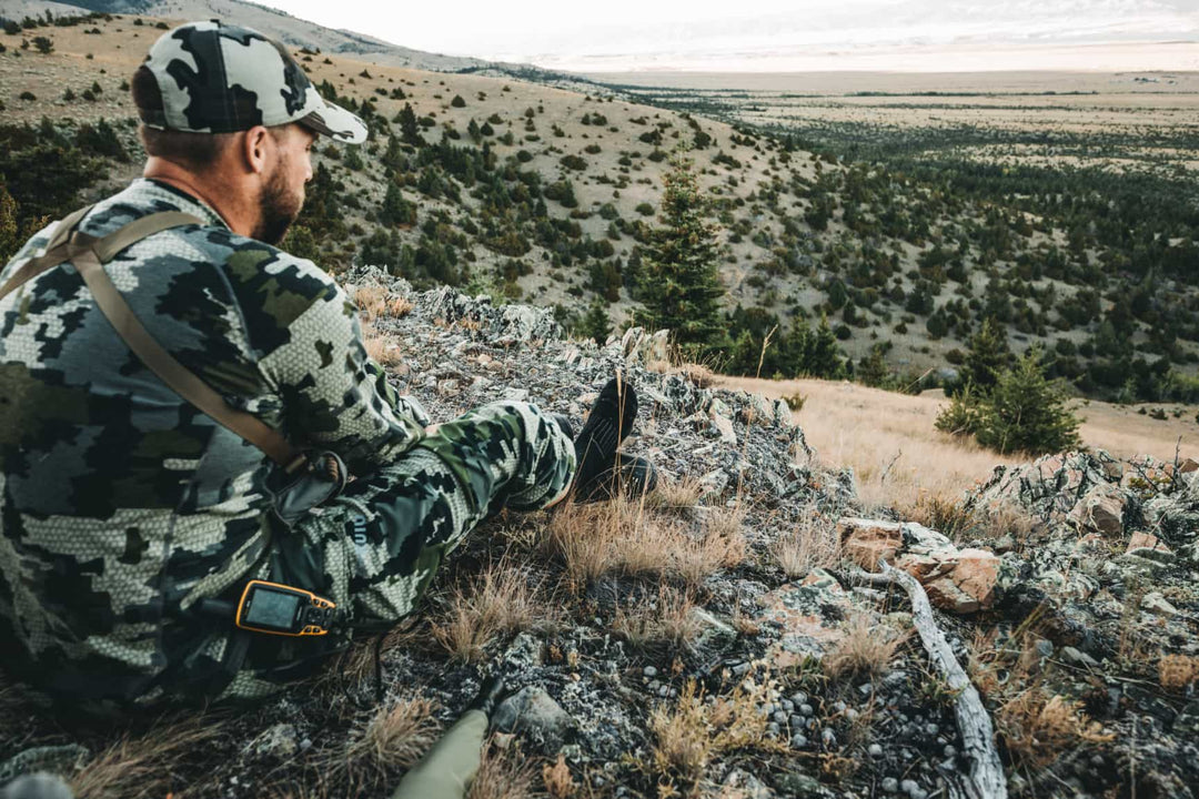 Male hunter seated on ridge giving his feet a break in comfortable darn tough socks