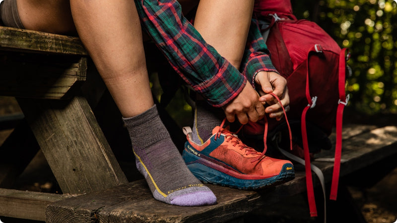 A hiker sitting at a picnic table wearing Darn Tough quarter hiker socks