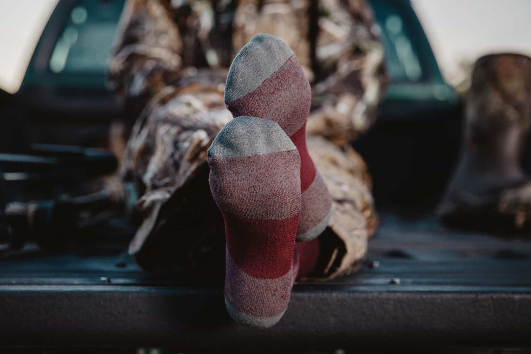 Hunter seated in truck bed so you can see the durable socks he's wearing for hunting