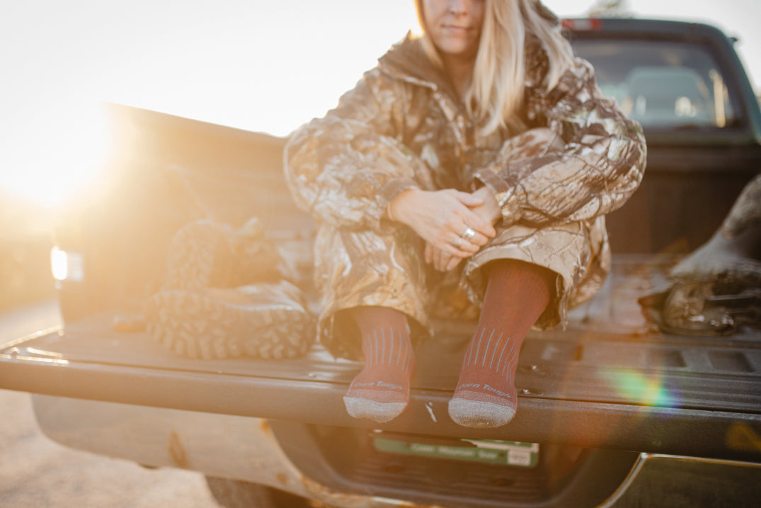 Woman hunter stead on tailgate wearing darn tough hunting socks for women