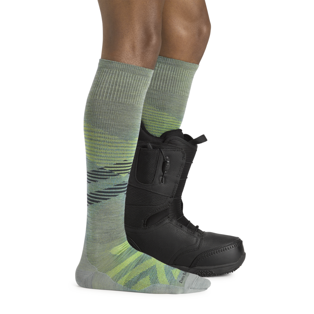 Man wearing Men's Pennant RFL Over-the-Calf Ultra-Lightweight Ski and Snowboard Sock in seafoam and one snowboard boot
