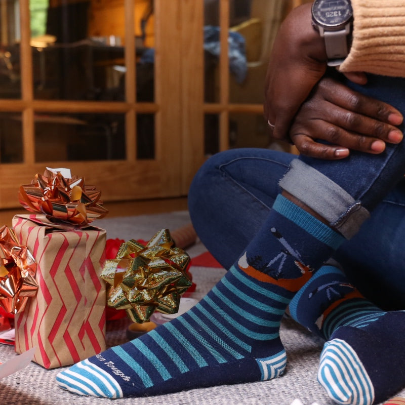 Feet in Darn Tough socks surrounded by wrapping paper and bows