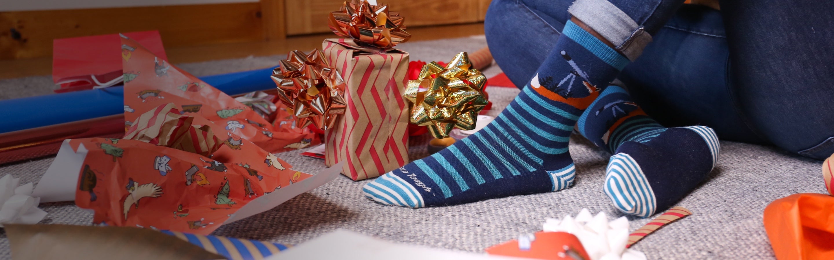 Feet in Darn Tough socks surrounded by wrapping paper and bows