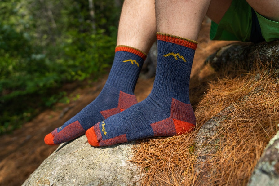 Feet wearing blue hiking socks with red heels and toes, the 1466 sock in denim