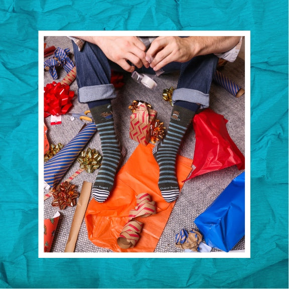 A pair of feet in Darn Tough socks surrounded by gift wrap supplies