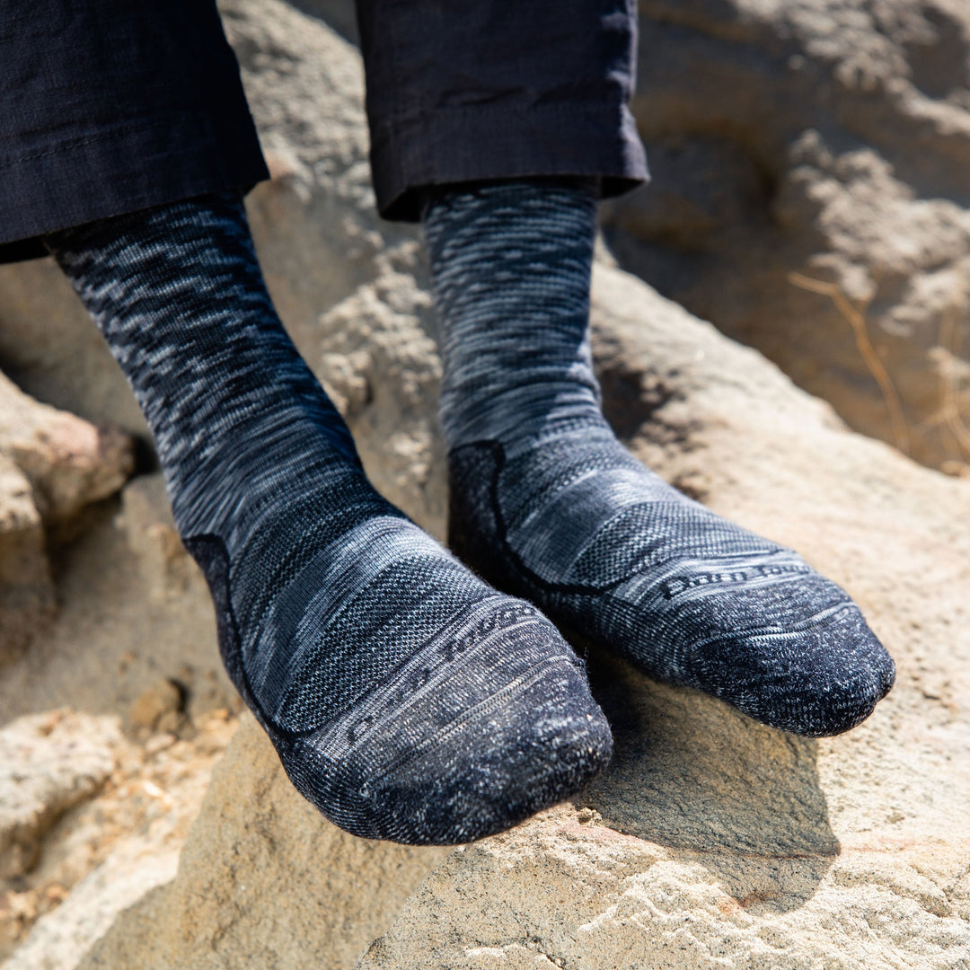 Close up shot of model sitting on a rock outside wearing women's light hiker micro crew hiking sock in space gray