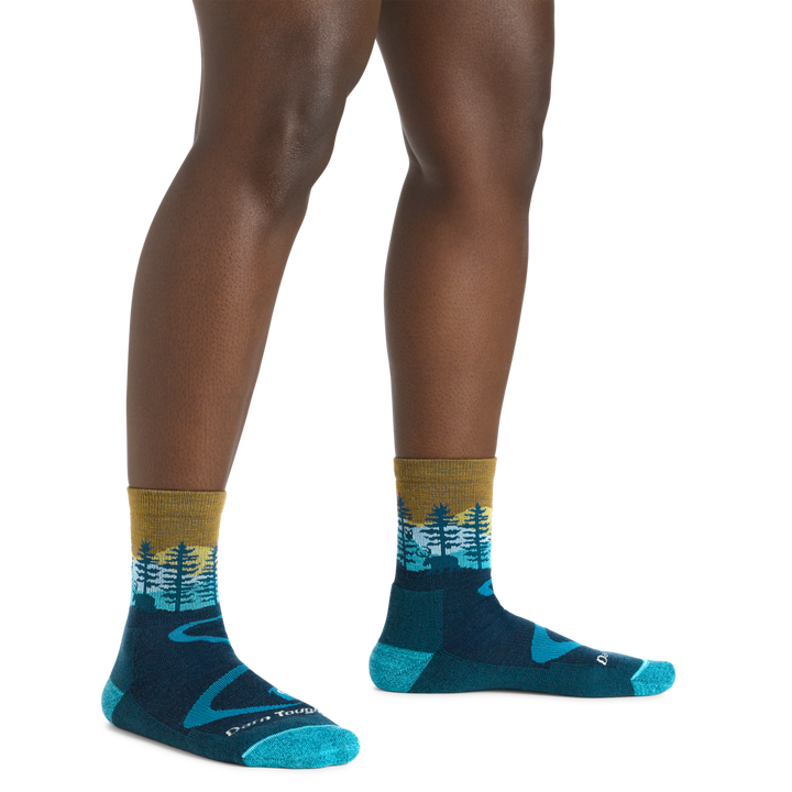 Model Wearing Women's Nortwoods Micro Crew Midweight Hiking Sock In Dark Teal color featuring a "beer" in the forest