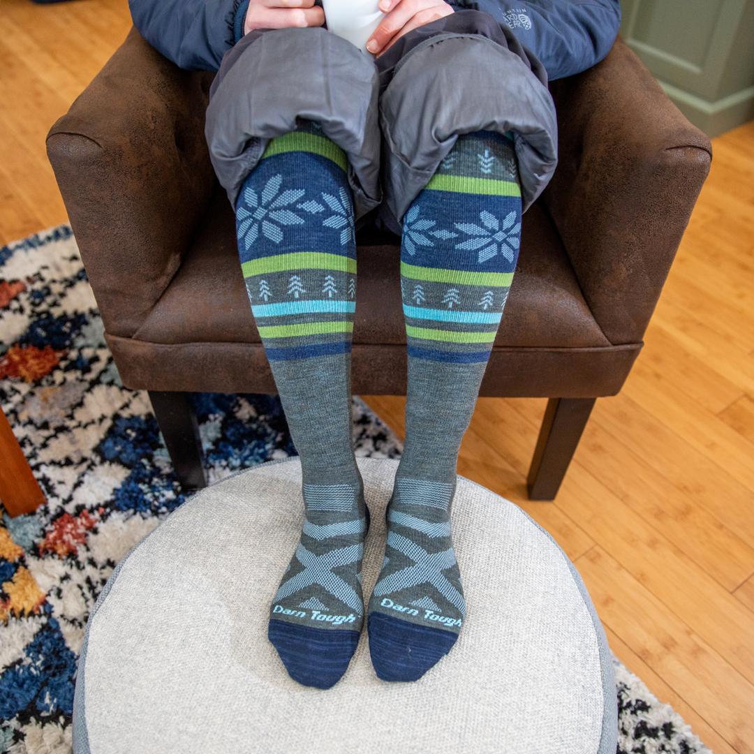 Skier seated indoors with boots off, wearing 8021 alpine socks from darn tough vermont