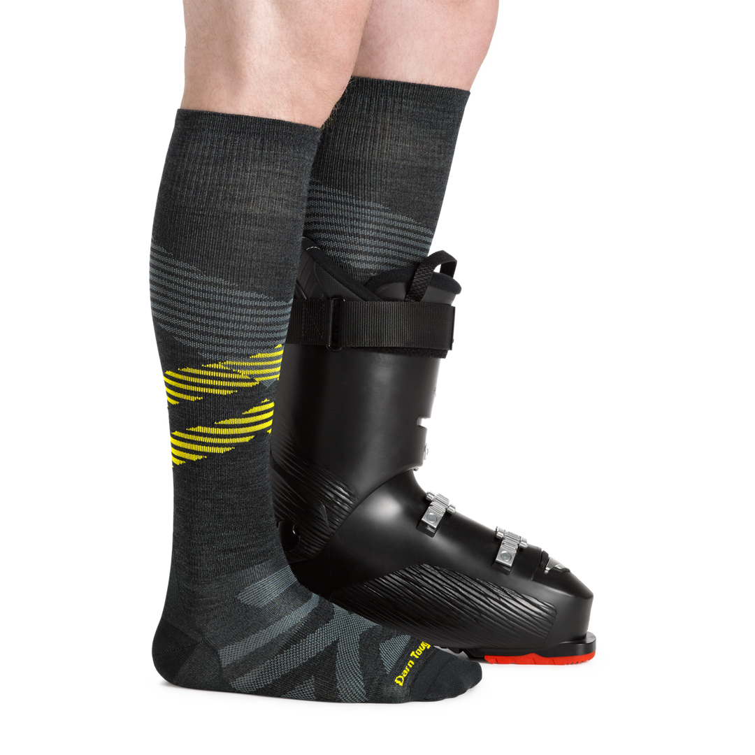 Man wearing Men's Pennant RFL Over-the-Calf Ultra-Lightweight Ski and Snowboard Sock in carbon and one snowboard boot