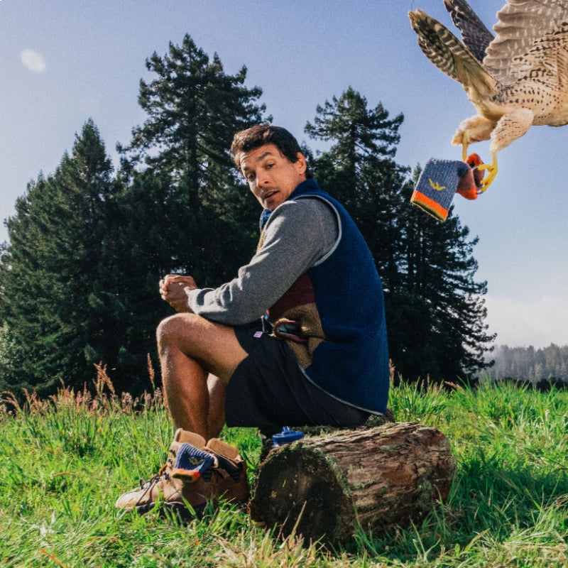 A hiker looking on in shock as a falcon flies off with one of his Darn Tough socks