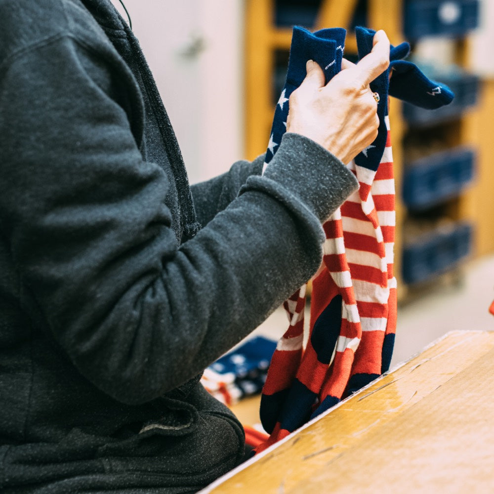 Woman at Darn Tough Mill holding red, white, and blue socks that are made in the usa