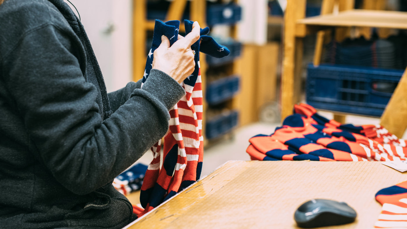 Woman at Darn Tough Mill holding red, white, and blue socks that are made in the usa