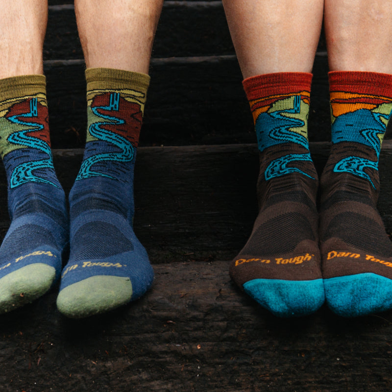 Two pairs of feet in matching Darn Tough socks with a waterfall design