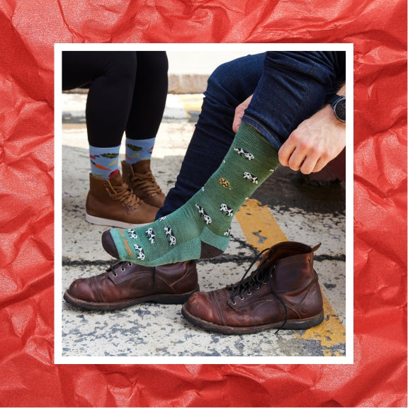 Feet putting on the Dairy Air sock; every purchase gives back to the Vermont Foodbank