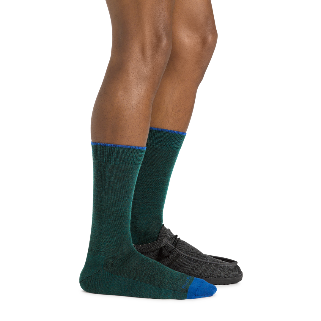 Model wearing the Men's Solid Crew Lightweight Lifestyle Sock in Bottle with a black loafer on onefoot