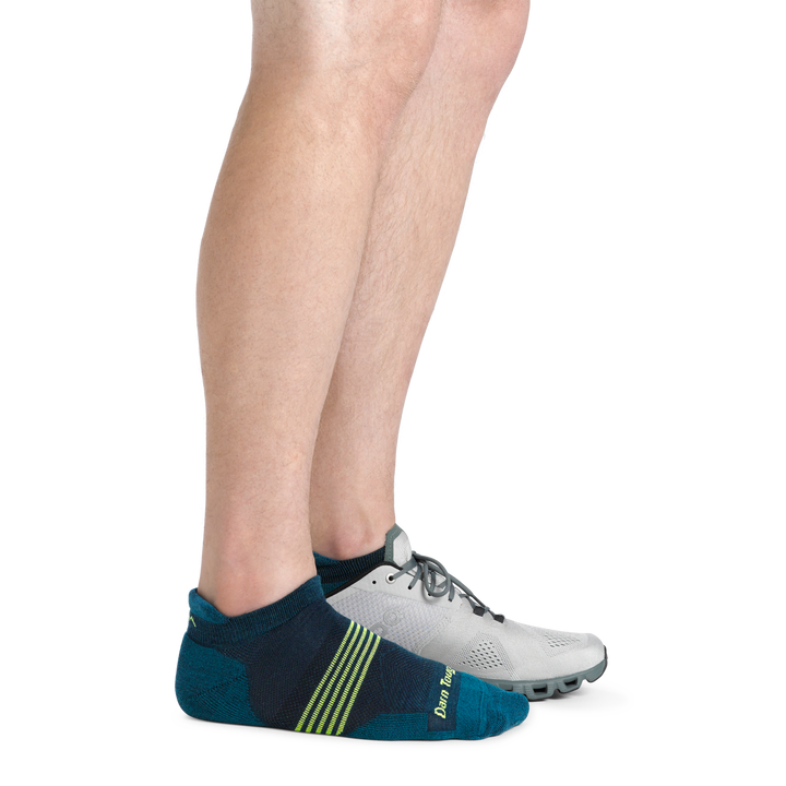 Man wearing Element No Show Tab Lightweight Running Sock in Blue with lime Green stripes and a running shoe on back foot