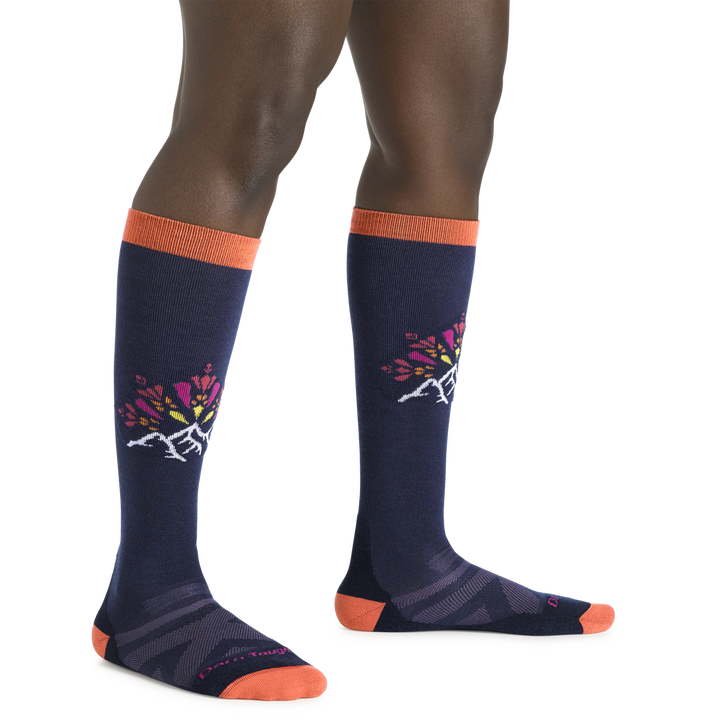 Model wearing Women's Daybreak Over-the-Calf Ski and Snowboard Socks in Navy and orange with mountain graphic