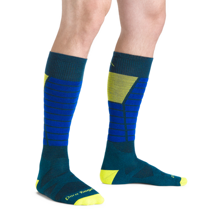 Model wearing Men's Function X Over-the-Calf Ski and Snowboard Sock in blue and green with shin padding