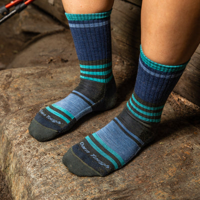 Hiker standing on a rock wearing the women's Her Spur hiking boot socks in blue