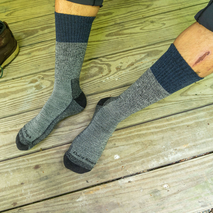 Lifestyle image shot looking down at a man's feet on a wooden deck, wearing Scout Boot Midweight Hiking Socks in Denim, Lifestyle Image