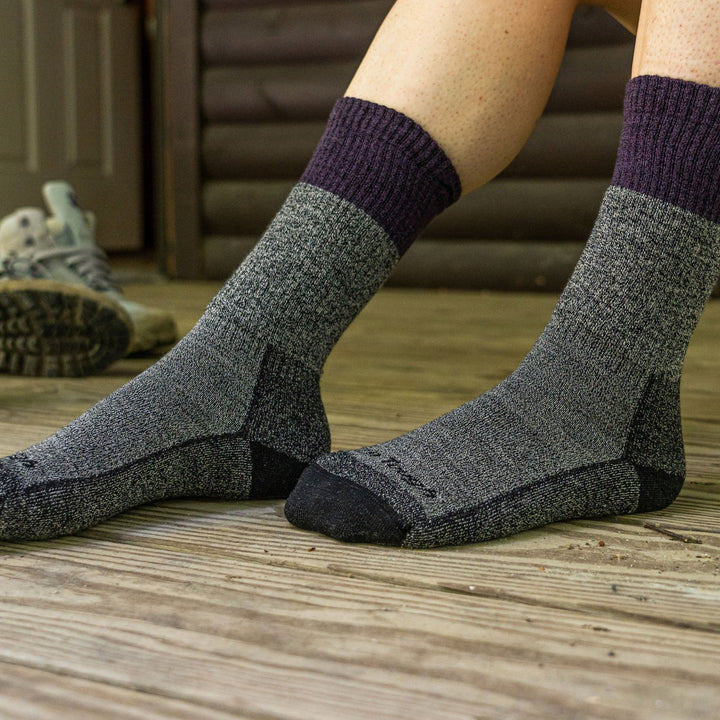 Close up of a woman's feet resting on a wooden porch wearing Women's Scout Boot Midweight Hiking Socks in Plum, Lifestyle Image