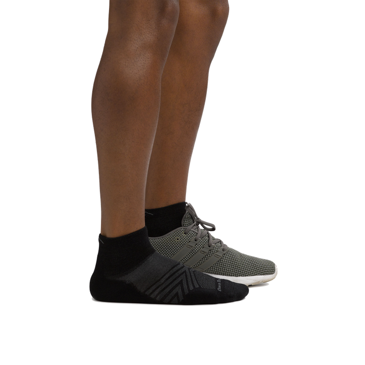 Profile of male legs facing right wearing Coolmax Run Quarter Ultra-Lightweight Running Sock in Black with back foot in a running shoe