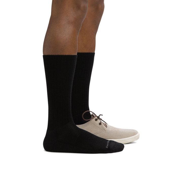 Side shot of model wearing men's the standard crew lifestyle sock in black with a tan shoe on his left foot