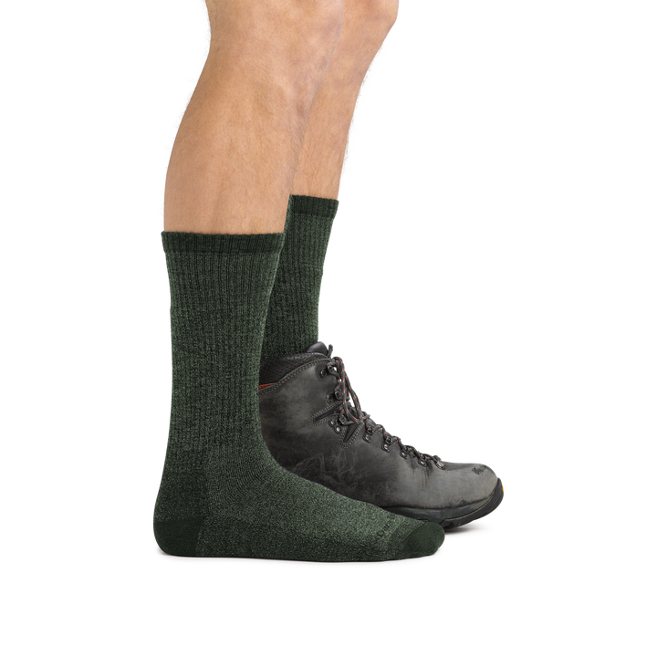 Profile image of male legs facing right wearing Nomad Boot Midweight Hiking Socks in Moss, with back foot also wearing a hiking boot