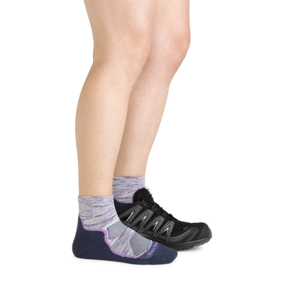 Side shot of model wearing the women's light hiker quarter hiking sock in cosmic purple with a black sneaker on her left foot