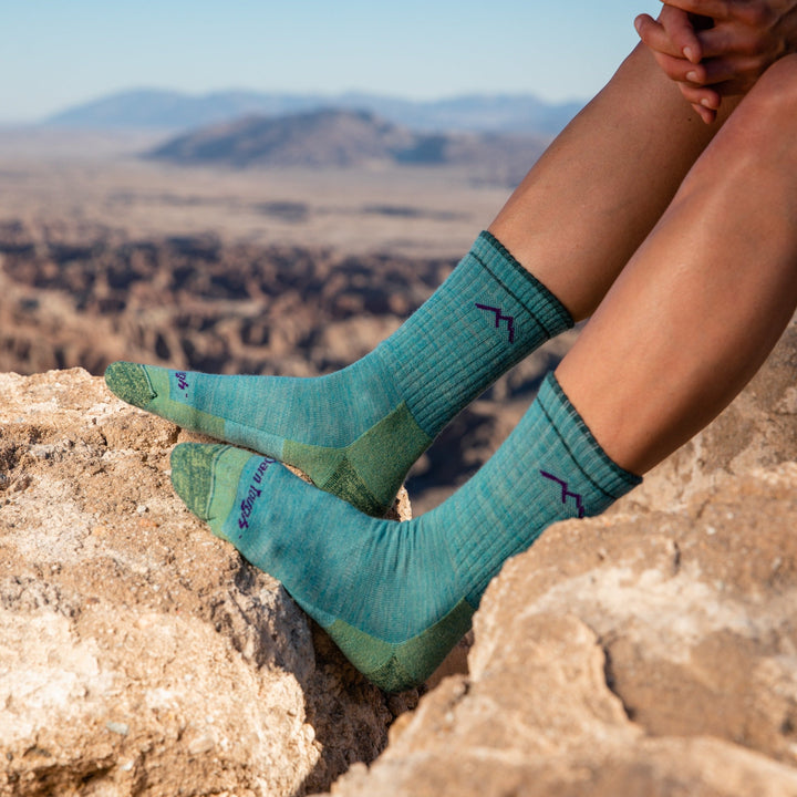 Close up shot of model wearing women's hiker micro crew hiking sock in aqua heather with mountains in the background