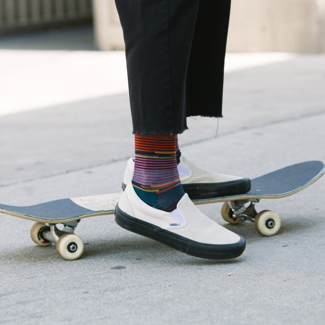 Close up shot of model on a skateboard wearing the women's pixie crew lifestyle sock in navy and white skate shoes