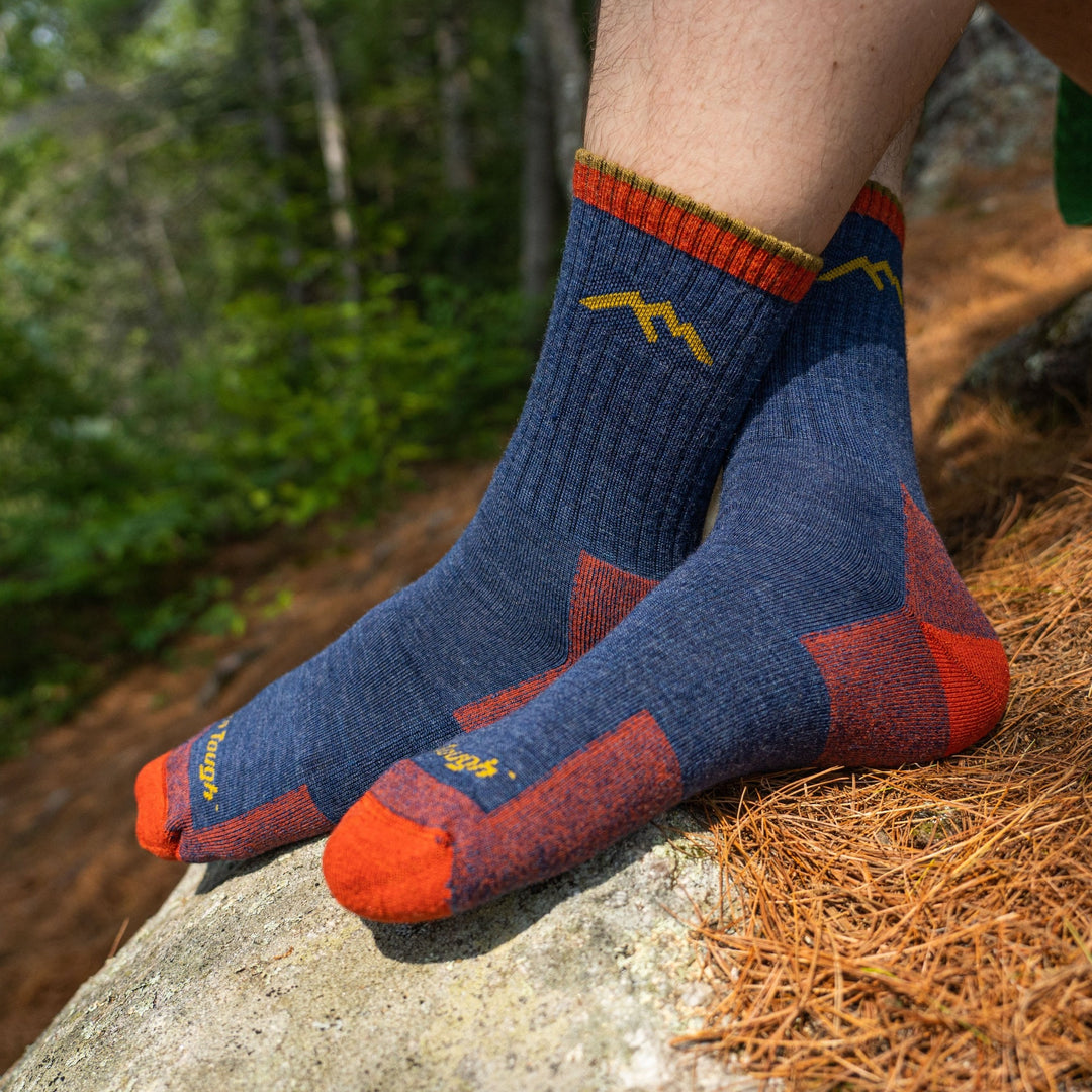 Close up shot of model sitting on a hiking trail wearing men's micro crew hiking sock in denim blue