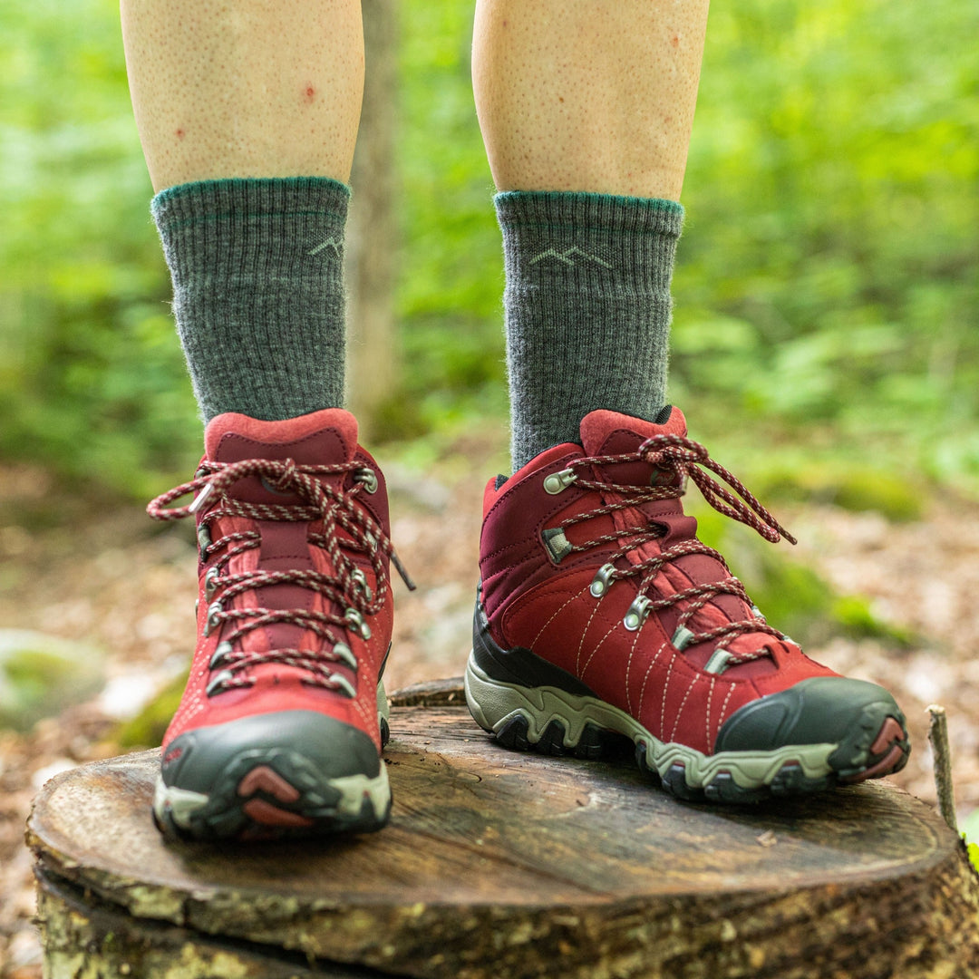 Close up shot of model standing on a tree stump wearing the women's boot hiking socks in slate with red hiking shoes on