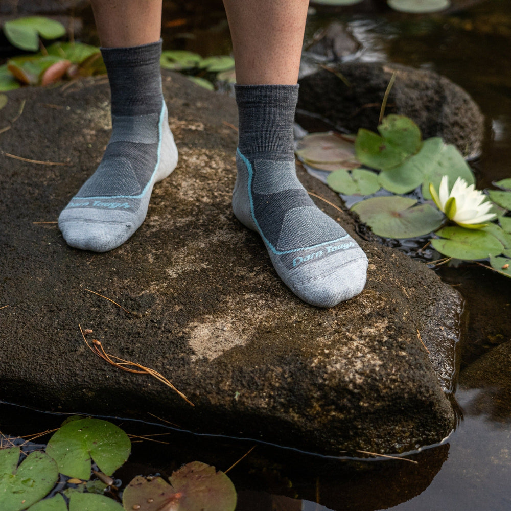 Model standing on a river rock wearing women's 1987 light quarter hiking sock in slate 