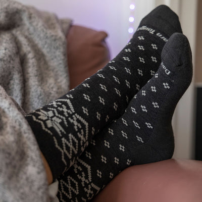 lifestyle image of model wearing shetland crew socks in charcoal, with feet crossed.