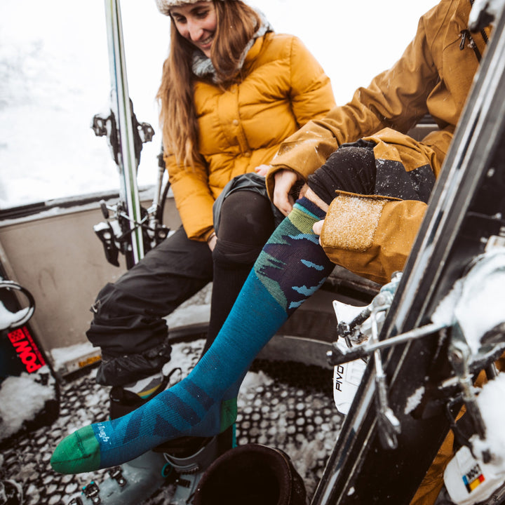 model wearing solstice ski socks while booting up to go skiing at the resort.